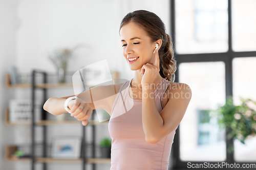 Image of woman with smart watch and earphones doing sports