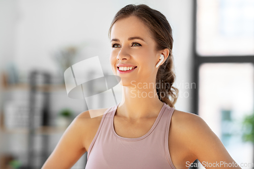 Image of smiling woman with earphones exercising at home