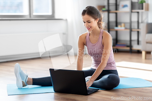 Image of woman with laptop computer doing sports at home