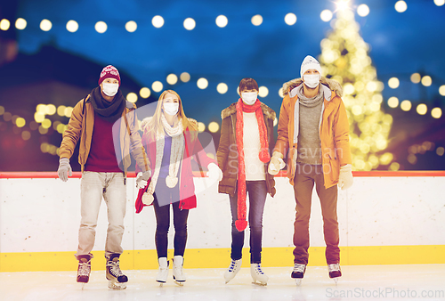 Image of friends in masks on christmas skating rink