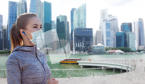 Image of woman in mask with earphones over singapore city