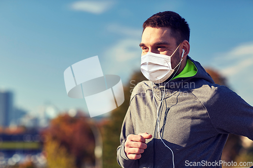 Image of man in mask with earphones running in city