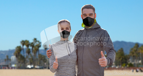 Image of couple in masks and sportswear showing thumbs up