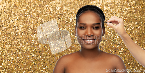 Image of face of african woman and hand with mascara brush