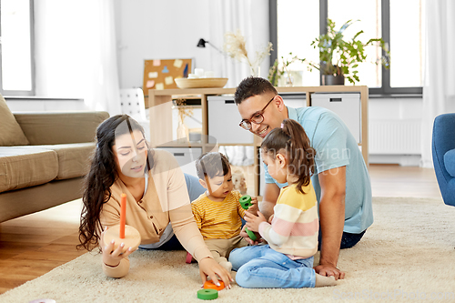 Image of happy family playing with pyramid toy at home