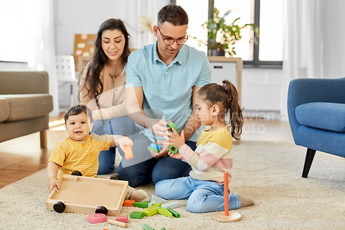 Image of happy family palying with wooden toys at home