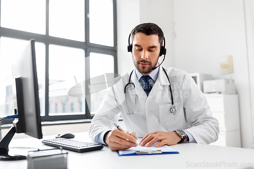 Image of male doctor with headset and clipboard at hospital