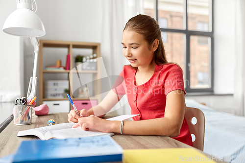 Image of student girl with book writing to notebook at home