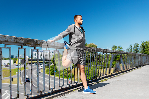 Image of man stretching leg on bridge