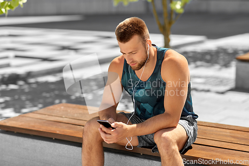Image of young athlete man with earphones and smartphone