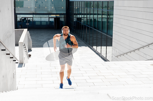 Image of young man in headphones running upstairs outdoors