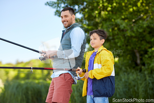 Image of happy smiling father and son fishing on river