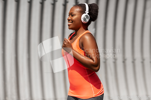 Image of happy african american woman running outdoors