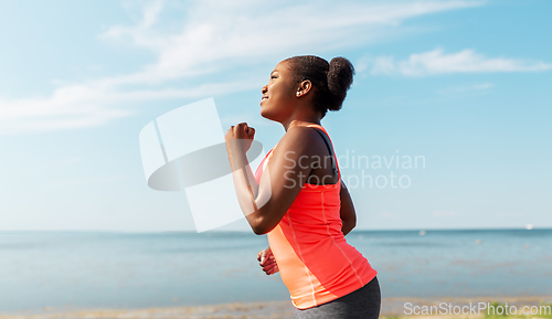 Image of young african american woman running at seaside