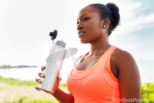 Image of african american woman drinking water after sports