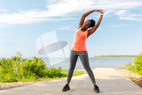 Image of young african american woman exercising on beach