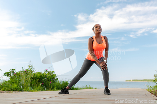 Image of young african american woman exercising on beach