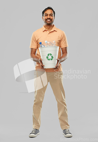 Image of smiling young indian man sorting plastic waste