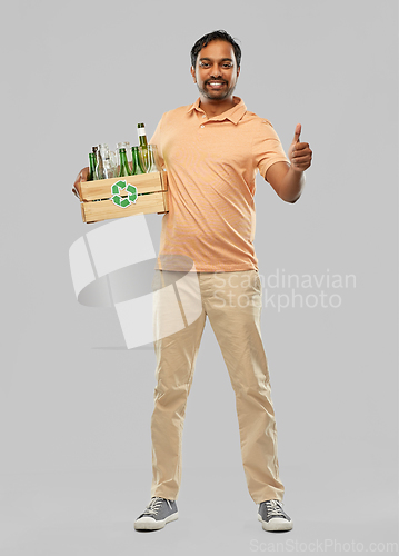 Image of smiling young indian man sorting glass waste
