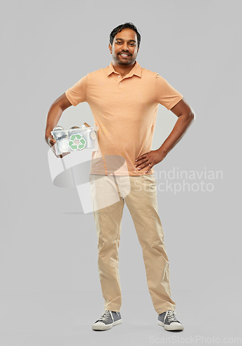 Image of smiling young indian man sorting metallic waste