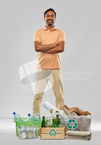 Image of smiling man sorting paper, glass and plastic waste