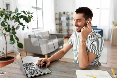 Image of man with laptop and earphones at home office