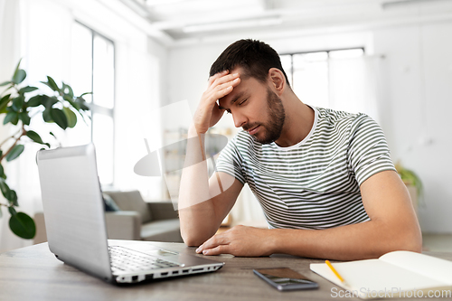 Image of stressed man with laptop working at home office