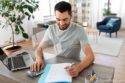 Image of man with files and calculator works at home office