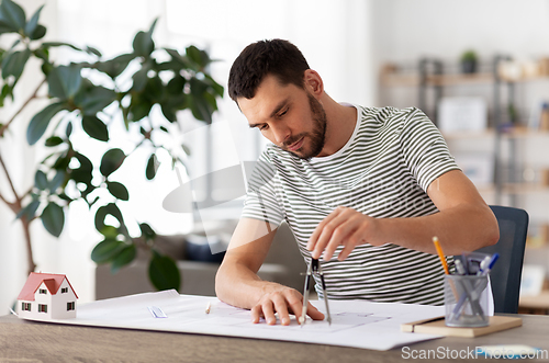 Image of architect with blueprint working at home office