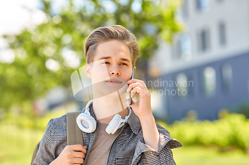 Image of teenage student boy calling on smartphone in city