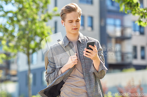 Image of teenage boy with earphones and smartphone in city