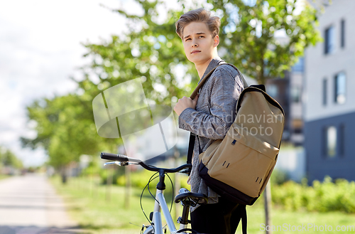 Image of young man with bicycle and backpack on city street