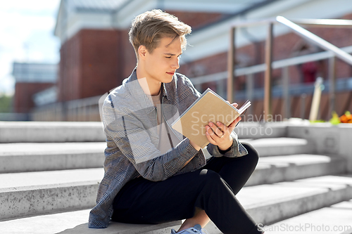 Image of young man with notebook or sketchbook in city