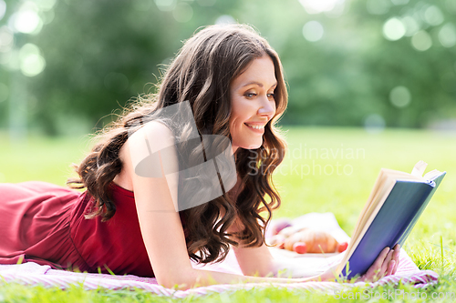 Image of happy smiling woman reading book at summer park