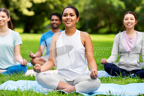 Image of group of happy people doing yoga at summer park