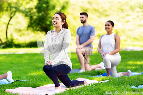Image of group of people doing yoga at summer park