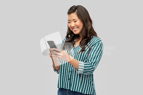 Image of happy asian woman using smartphone