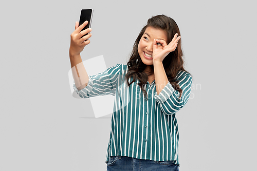 Image of smiling asian woman taking selfie by smartphone