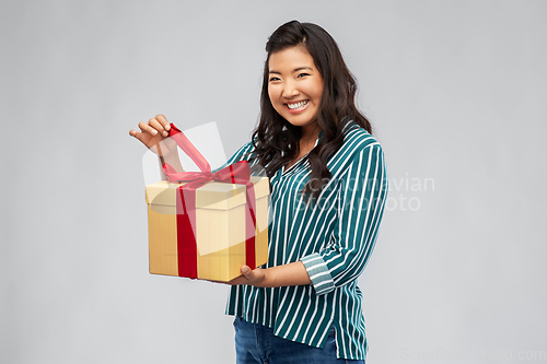 Image of happy asian woman opening gift box