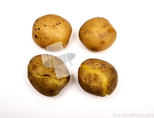 Image of four boiled potatoes in their skins on a white 