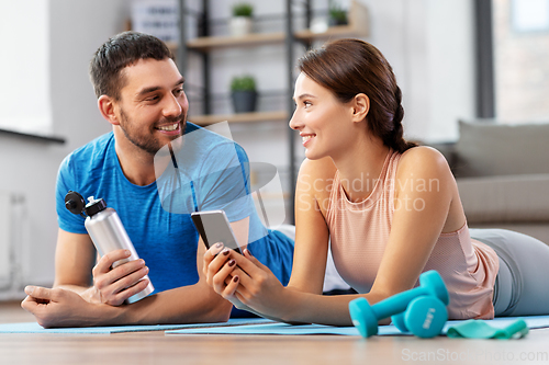 Image of happy couple with smartphone after sports at home