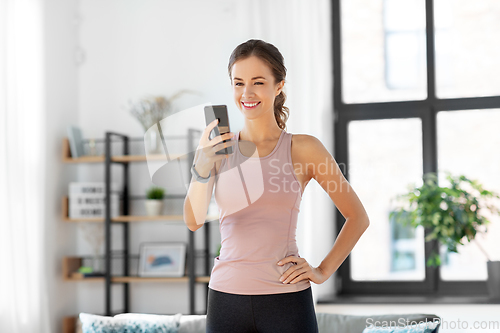 Image of young woman with smatphone exercising at home