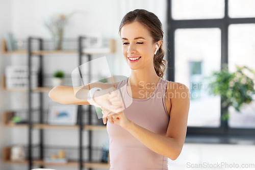 Image of woman with smart watch and earphones doing sports