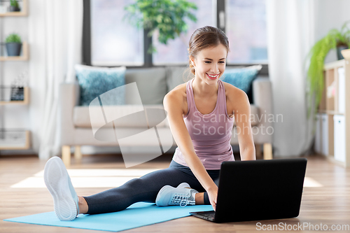 Image of woman with laptop computer doing sports at home