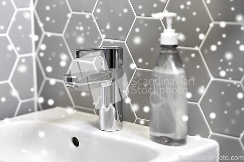 Image of close up of water tap with liquid soap on sink