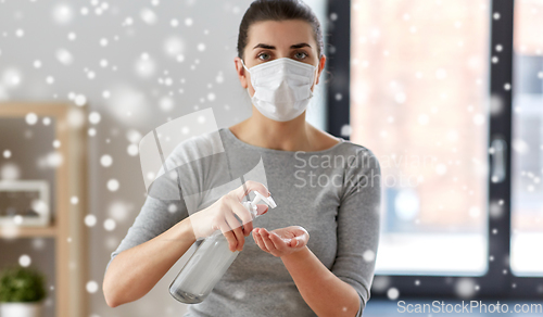Image of close up of woman in mask applying hand sanitizer