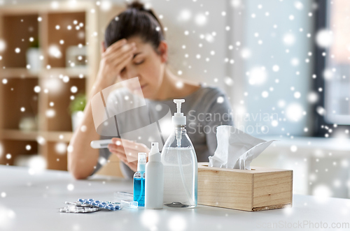 Image of medicines and sick woman with thermometer at home