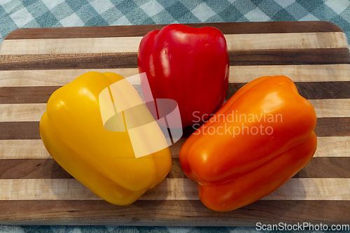 Image of Three Colored Bell Peppers on a Wood Cutting Board