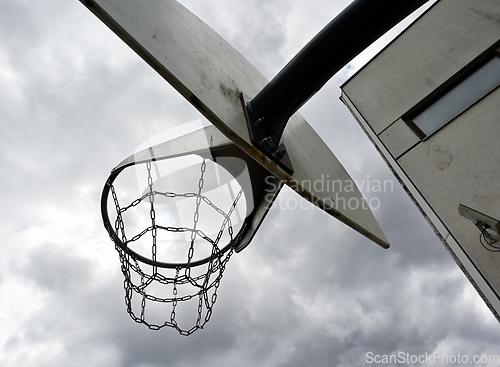 Image of an anti-vandal basketball hoop with iron chains against a gloomy