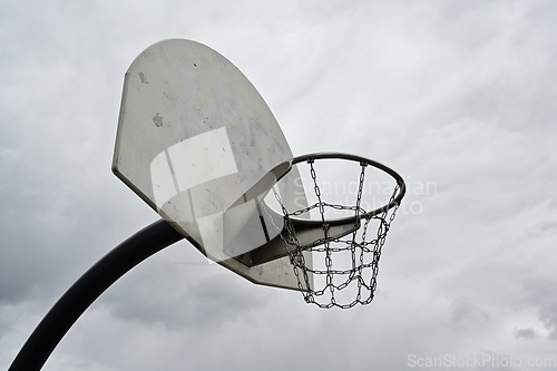 Image of an anti-vandal basketball hoop with iron chains against a gloomy